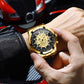 Gold-tone quartz skull watch with black dial skeleton on wrist, metal bracelet