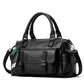 Black pebbled leather handbag with top handles, crossbody strap, and front flap pocket