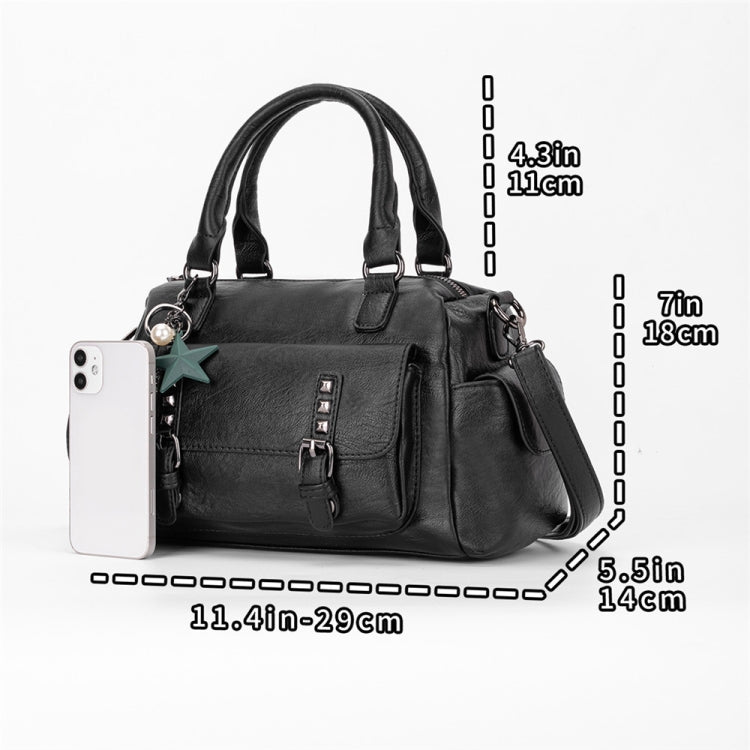 Black pebbled leather handbag with crossbody strap and front flap pocket, beside smartphone