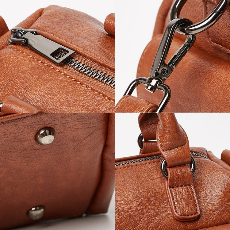 Brown leather handbag detail close-up of zipper pull, studs, and metal strap clip