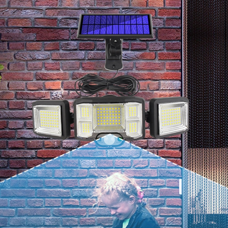 Solar wall flood light with triple LED heads and motion sensor mounted on a wall, black