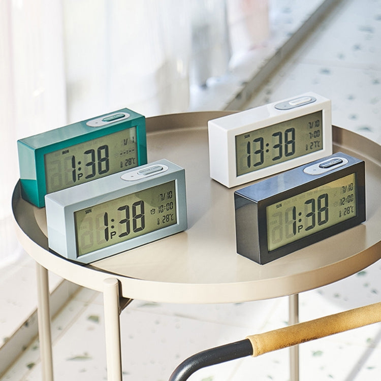 Bedside digital alarm clocks in black, white, and turquoise on a round table