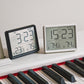Magnetic digital clocks in black and white displaying time and temperature