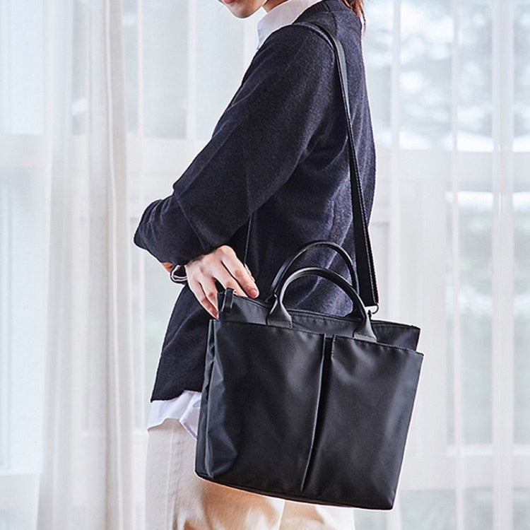 Black messenger bag with top handles and shoulder strap, zip-top and front pocket