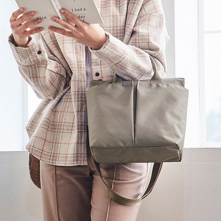 Light khaki tote-style messenger bag with zipper closure and wide interior, carried