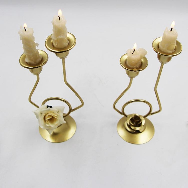 Two gold-tone double candle holders with lit cream candles and white rose