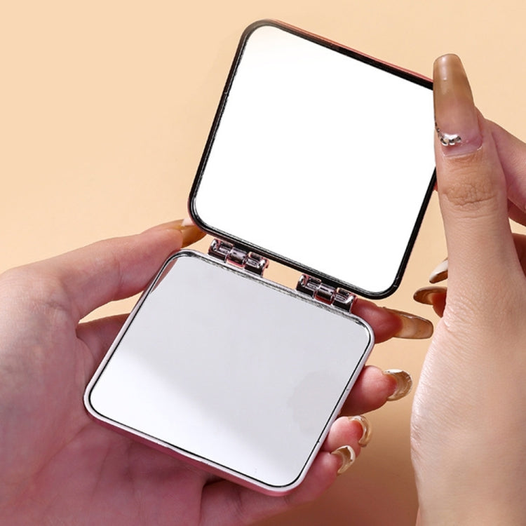 Mini folding double-sided makeup mirror held open with two white reflective faces