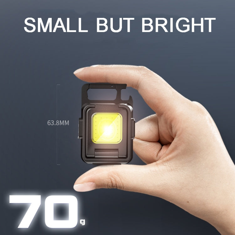 Small black COB keychain flashlight held in hand with one bright LED panel