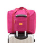 Pink trolley storage bag with front zip pocket and top handle, designed to slide over luggage
