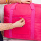 Bright pink trolley storage bag with front zip pocket, zipper being opened by hand