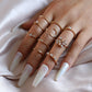 Close-up of gold-tone knuckle rings on hand with rhinestone crescent and heart stones