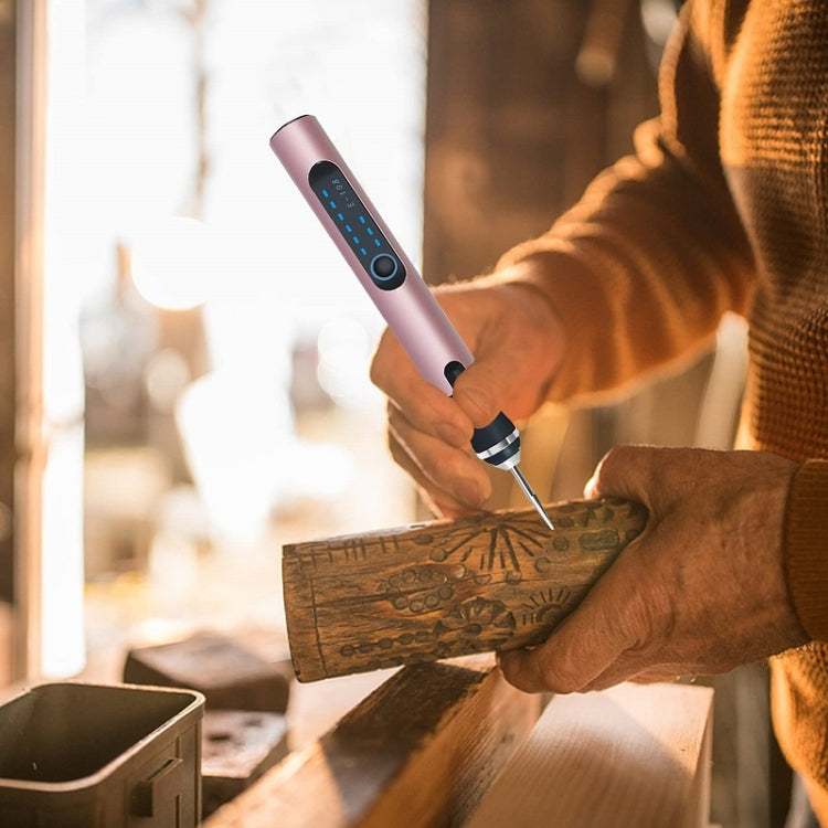 Rose gold mini electric drill pen in hand with metal tip carving a wooden block
