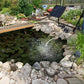 Solar aeration pump with solar panel over pond, producing water bubbling near rocks