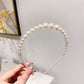 White pearl headband with round pearl beads and black attachment clips at the ends