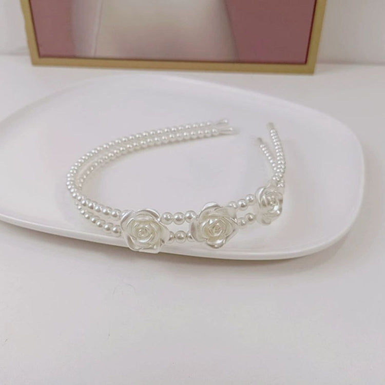 White pearl headband with three rows and two small rose appliques across the front
