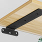 Black triangular shelf partition bracket plate with mounting holes on a wooden shelf