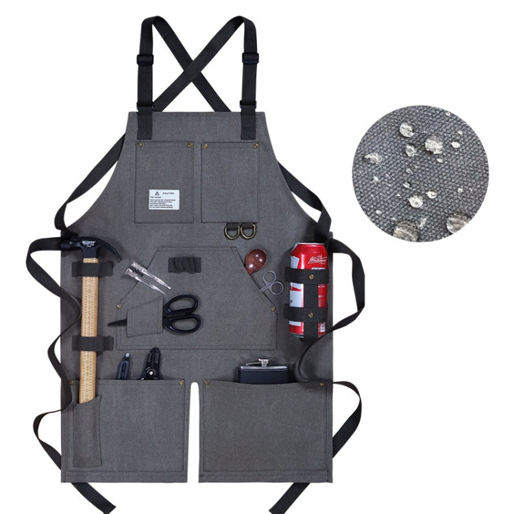 Gray canvas work apron with crossed back straps, multiple tool pockets, and clips