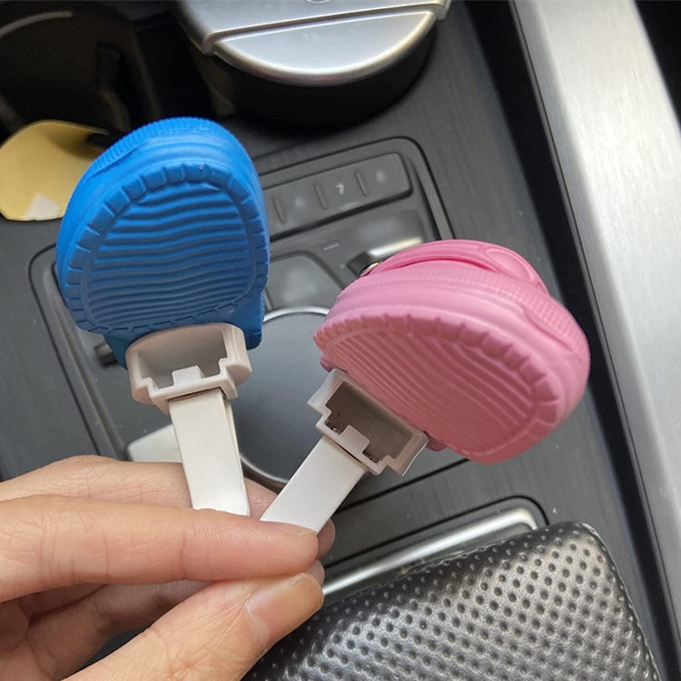 Blue and pink shoe-shaped car air vent ornaments on hands with white clips