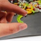 Hand holding a green plastic worm bait with red-tipped beads