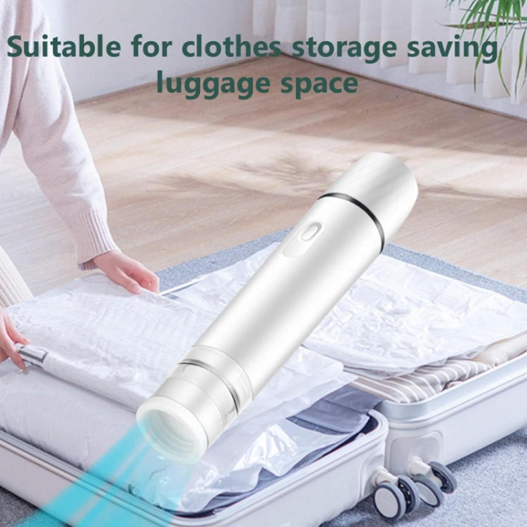 White handheld vacuum sealer compressing vacuum bag on folded clothes