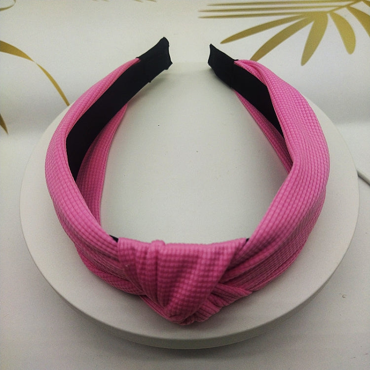Wide knotted headband in bright pink knit fabric with dark inner backing.