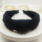 Wide knotted headband in black knit fabric with dark inner backing.