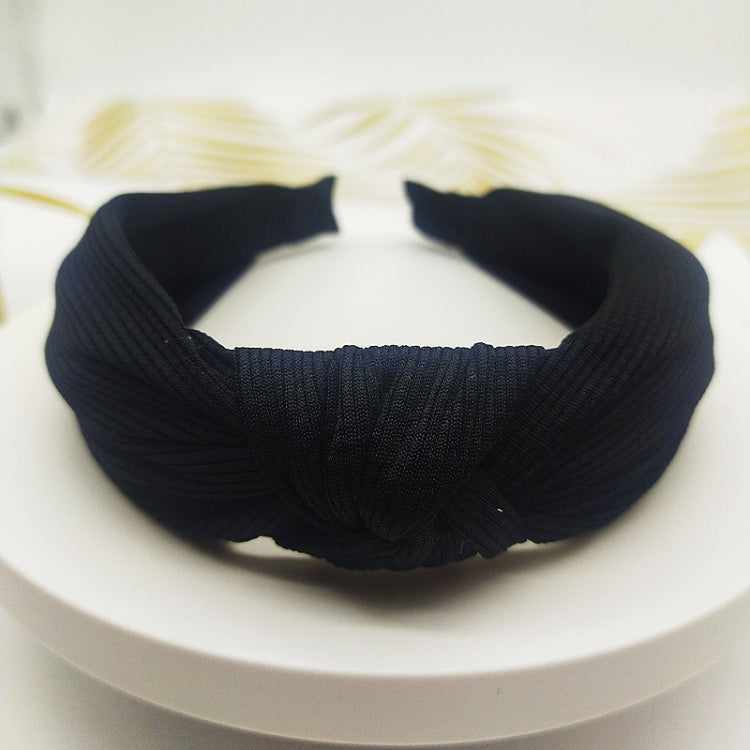 Wide knotted headband in black knit fabric with dark inner backing.