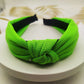 Wide knotted headband in fluorescent green knit fabric with dark inner backing.