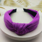 Wide knotted headband in purple knit fabric with dark inner backing.