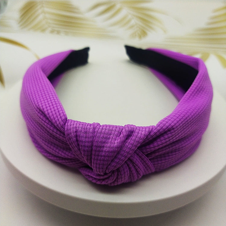 Wide knotted headband in purple knit fabric with dark inner backing.