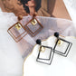 Alloy drop earrings in brown and black with gold-tone center charms and square frames