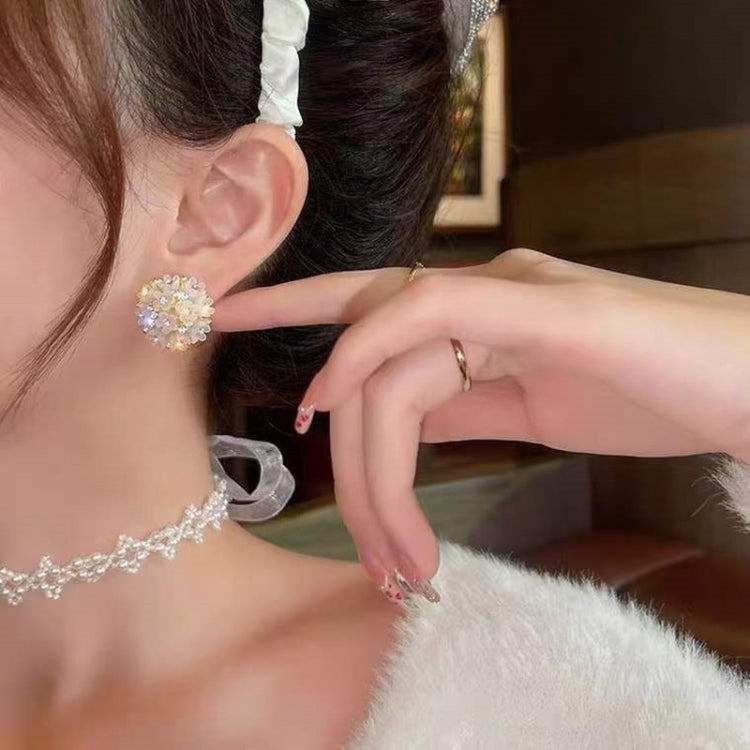 White crystal domed flower stud earrings near ear, gold-tone posts.