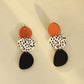 Dangle earrings with orange round tops, leopard print ovals, and black teardrop drops
