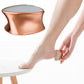 Rose gold handheld foot peeling grinder near bare foot, textured grinding head