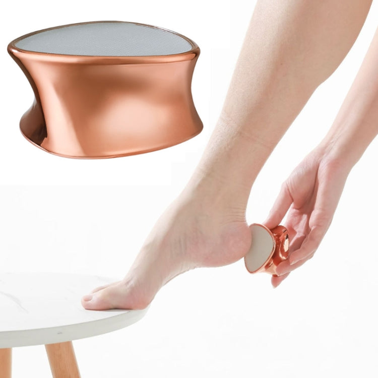 Rose gold handheld foot peeling grinder near bare foot, textured grinding head