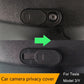 Camera privacy cover installed on black panel beside round lens opening