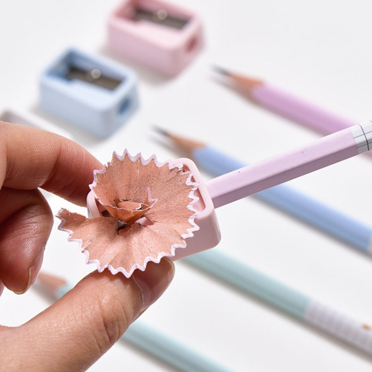 Hand holding pink mini pencil sharpener, releasing wood shavings from the blade