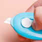 Blue mini utility knife close-up with white button and extended blade edge.