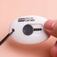 White mini utility knife with black button and extended blade, held between fingers.