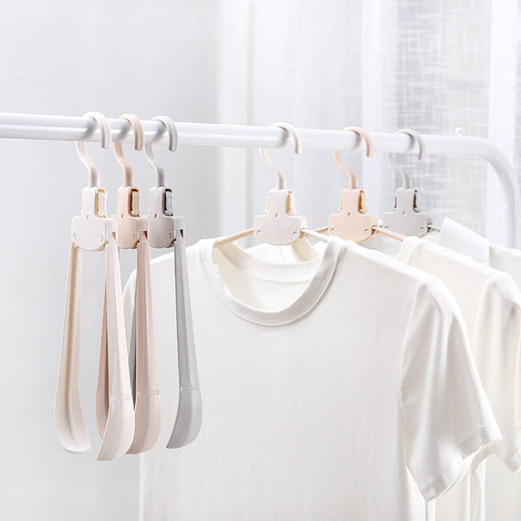 Multiple plastic folding hangers on a drying bar with white shirts