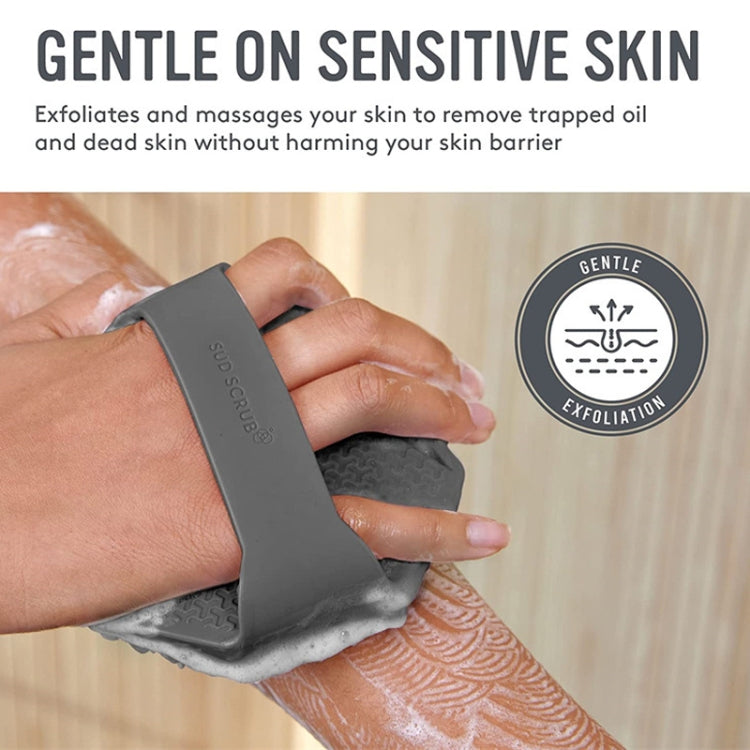 Grey silicone body bath brush with scrubbing fins held on wet skin in shower