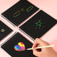 Black scratch art cards with spiral binding and hand using wooden scratching pen