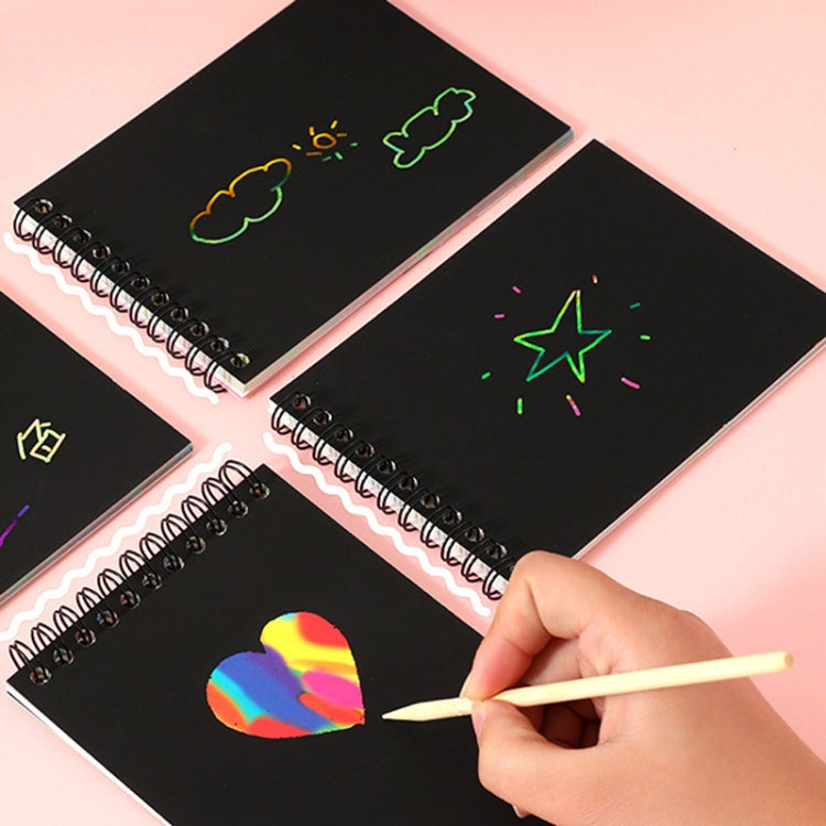Black scratch art cards with spiral binding and hand using wooden scratching pen