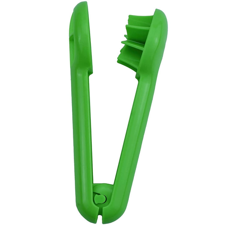 Green plastic fruit slicer tool with hinged slicing arms and curved handle