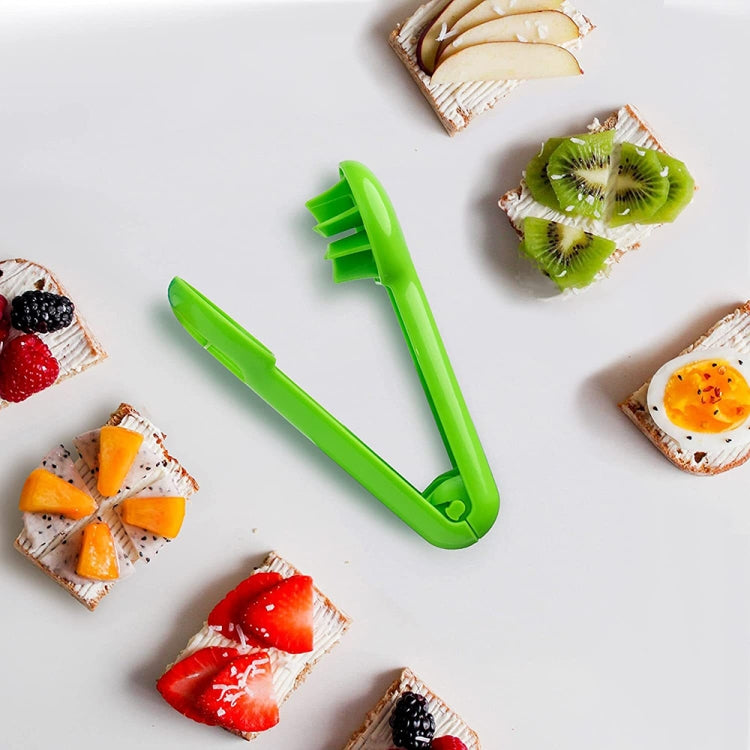 Green handheld fruit slicer tool set on a white surface