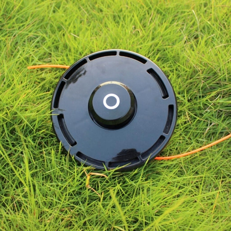 Trimmer head on grass with orange nylon line extending outward.
