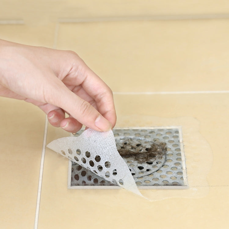 Hand lifting used disposable non-woven drain filter sticker from floor drain