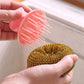 Gold and gray wire scrub ball held with pink comb tool for cleaning