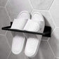 Wall-mounted metal rack with black shelf holding a pair of white slide slippers