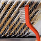 Orange-handled brush cleaning grime from a metal vent or grill grate.